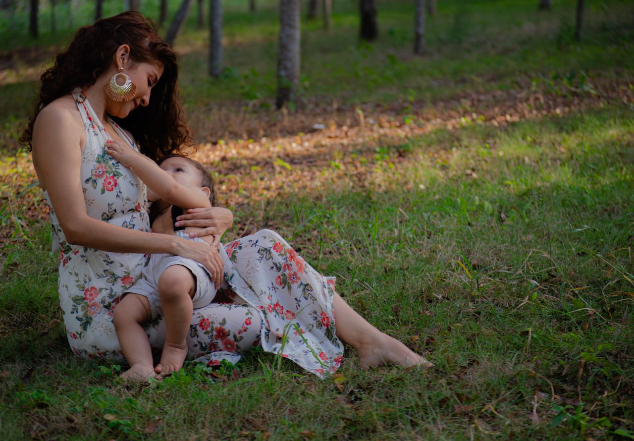 our-experience A mother lovingly breastfeeding her child in a peaceful outdoor setting.