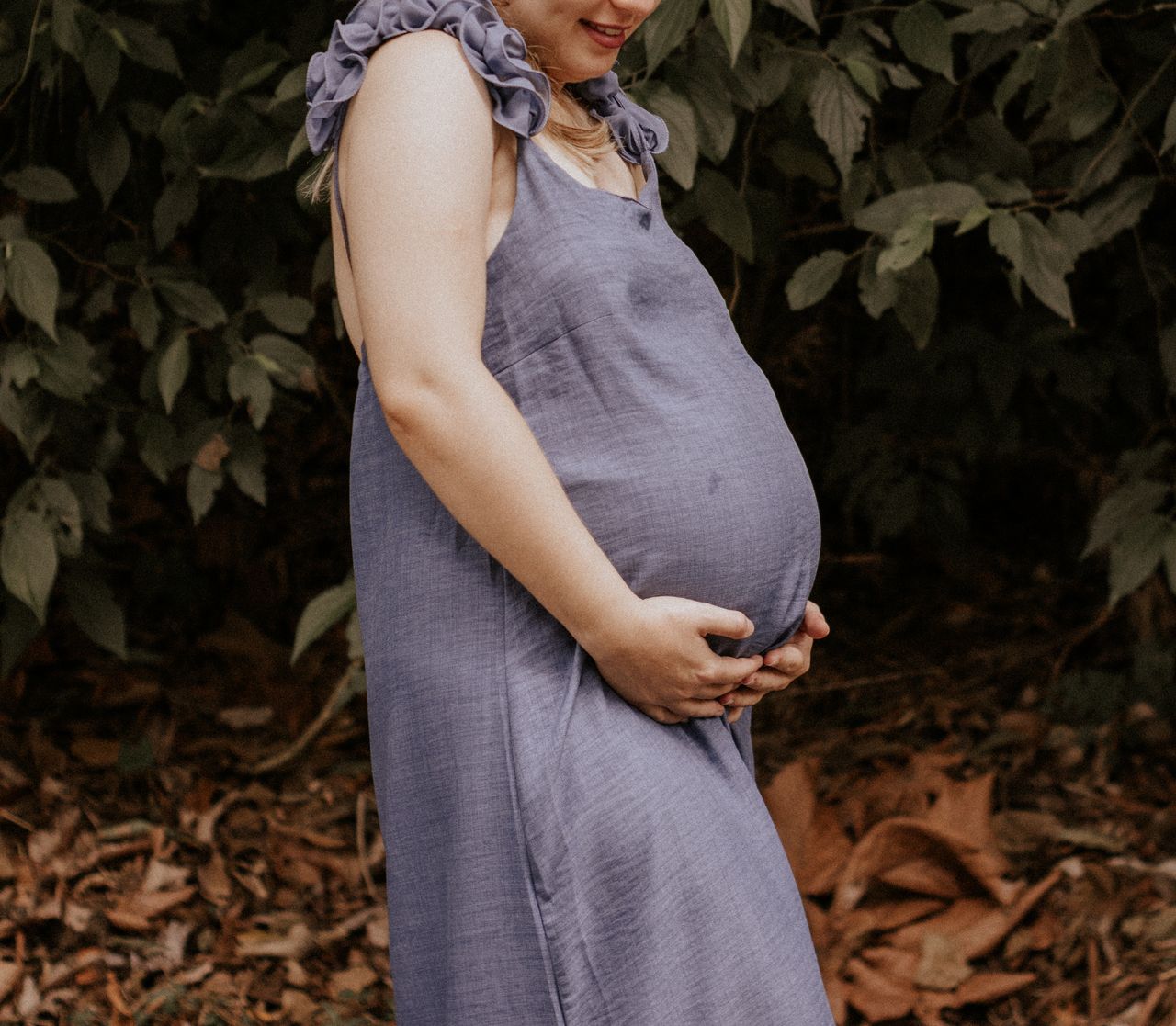 The Art of Drawing Readers In: Your attractive post title goes here A woman in a blue dress enjoying nature during pregnancy, standing outdoors.