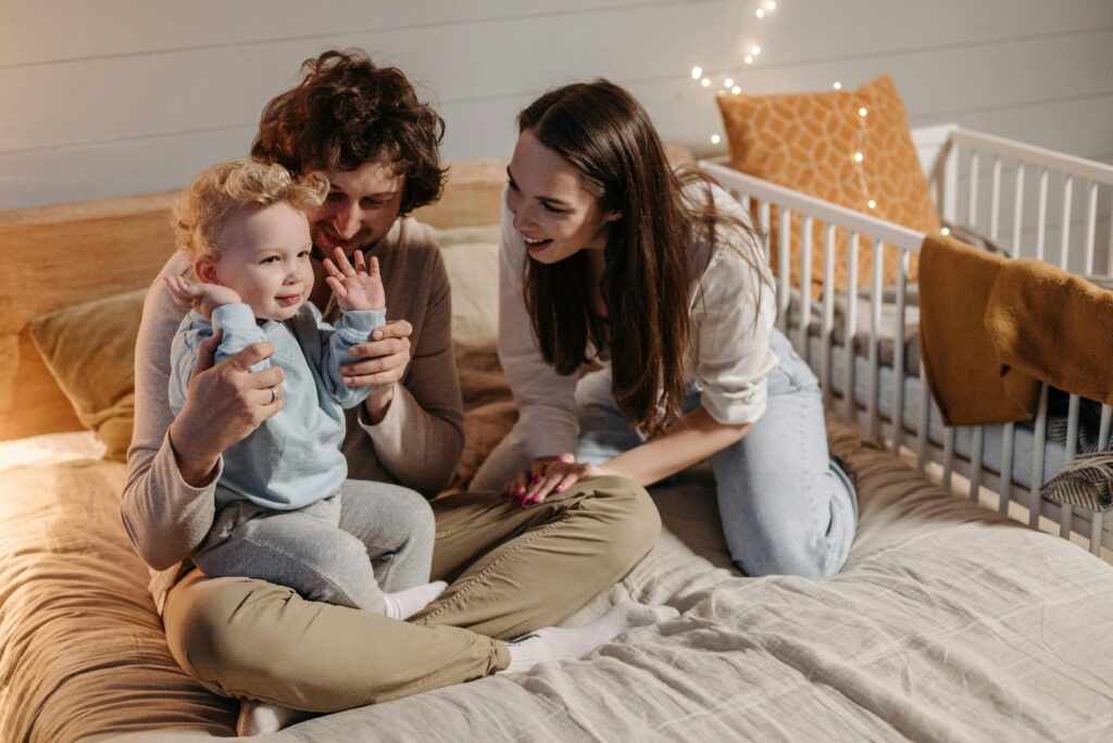 pexels photo 7938002 7938002 A joyful family moment with parents and child in a cozy bedroom, filled with warmth and laughter.